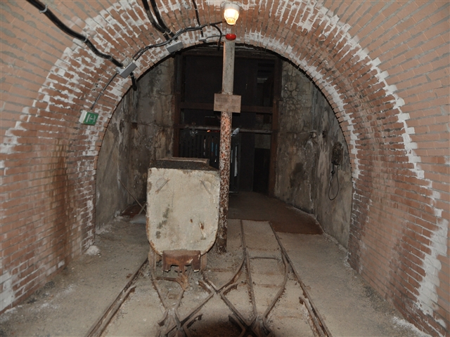 Un tunnel buio e roccioso con un carrello da miniera.